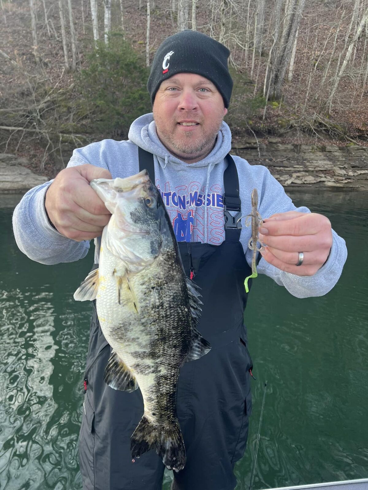 Person holding fish in front of woods and lake